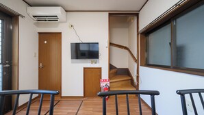 Un pasillo con piso de madera, un extintor, un televisor montado en la pared y una ventana.
