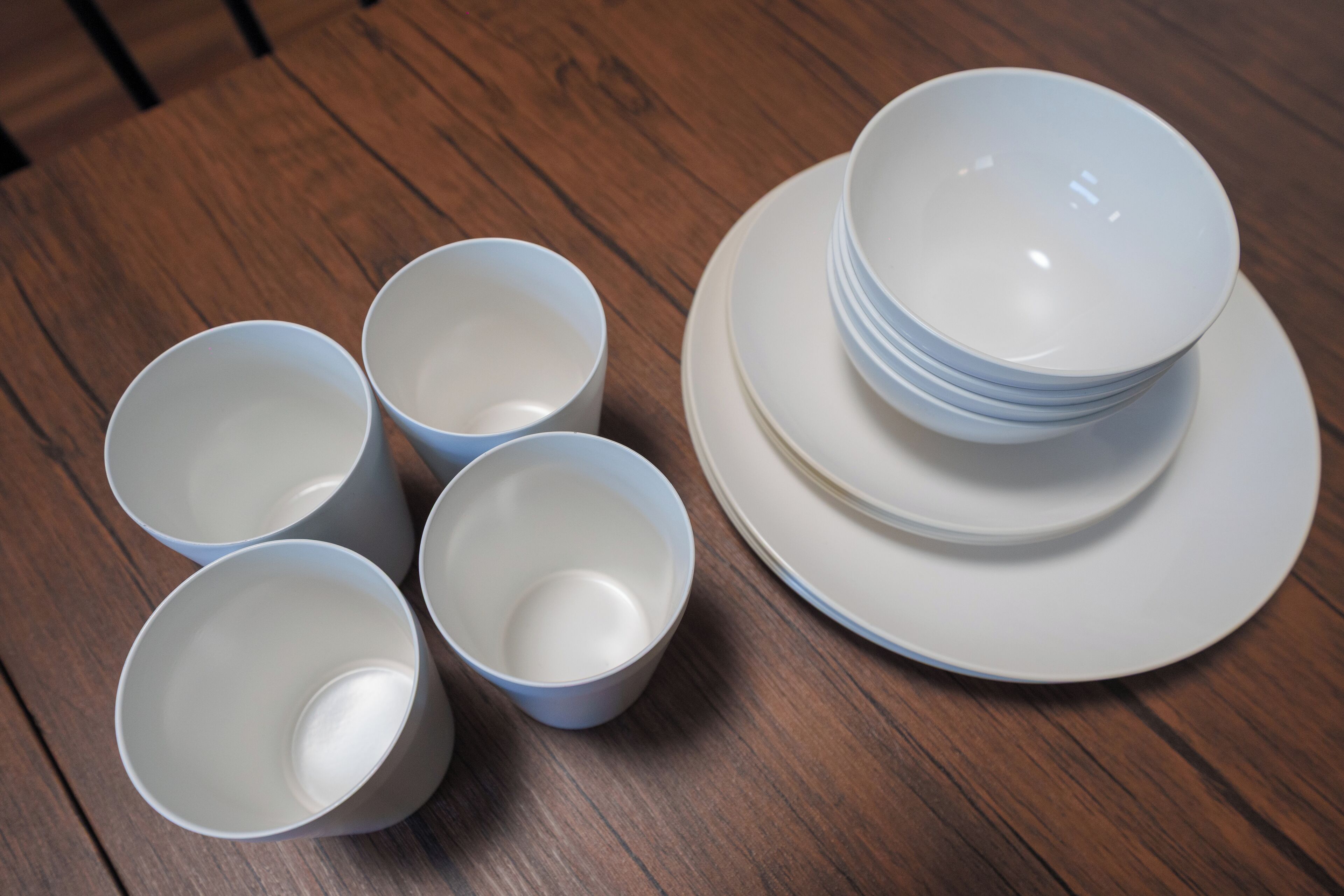 A set of white bowls and plates on a wooden table.