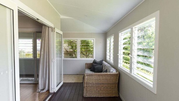 A room with a sliding glass door, a wicker sofa, and a view of greenery outside. - Saltwater ~ Cozy sanctuary by the sea (Bendalong)