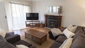 Ein Wohnzimmer mit Fernseher, Kamin und bequemen Sitzmöglichkeiten.