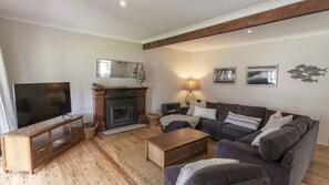 A living room with a fireplace, a television, a sofa, and a lamp. - Saltwater is a pet friendly home in Bendalong (Bendalong)
