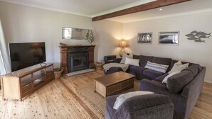 A living room with a fireplace, sofa, TV, and wooden flooring. - Saltwater ~ Cozy sanctuary by the sea (Bendalong)