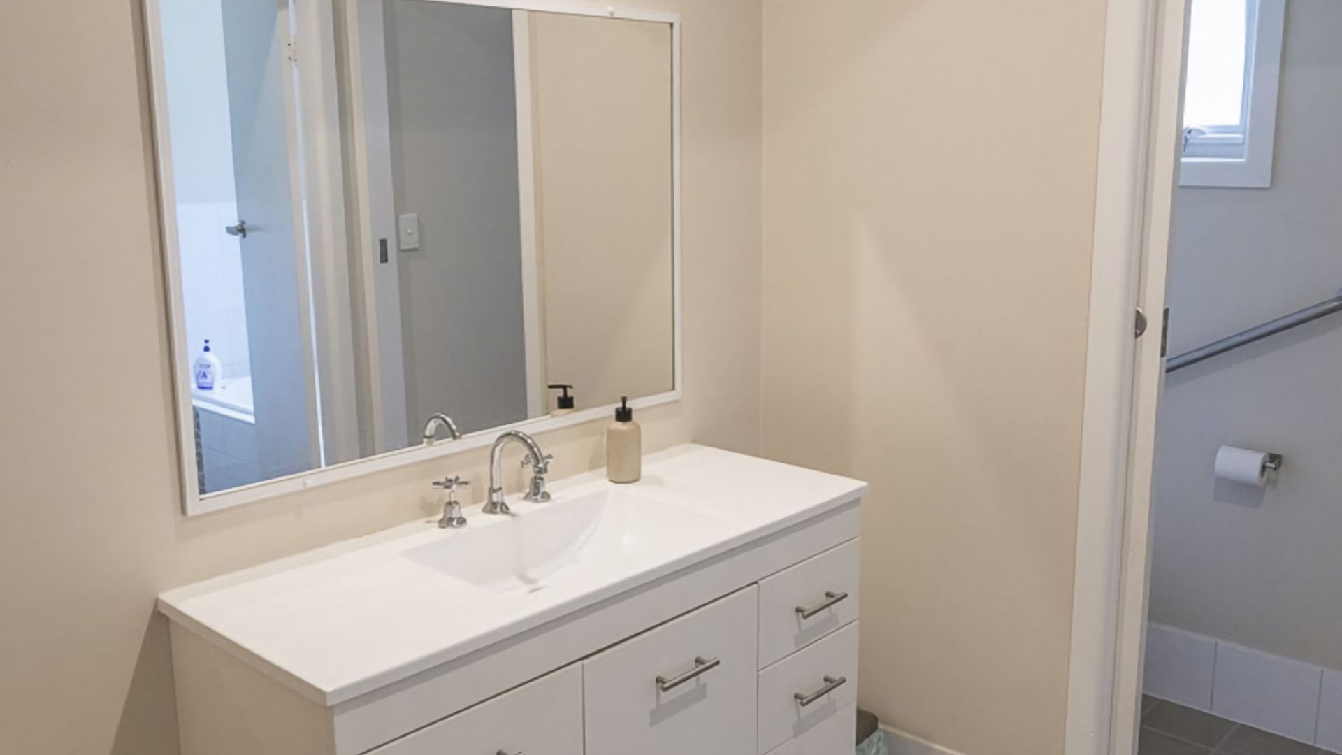 A bathroom with a white vanity, a large mirror, and a toilet.