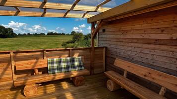 Um deck de madeira com bancos e vista para um campo.