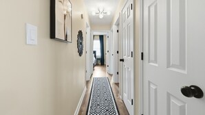 Un couloir avec un tapis à motifs, des portes blanches et un luminaire au plafond.
