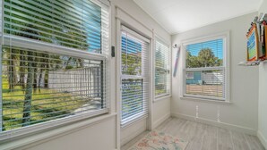 A room with large windows, a door, and a tiled floor.