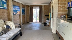 Een kamer met een bed, een televisie, een bureau en een schuifdeur die uitkomt op een balkon.