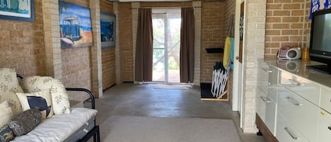 Une chambre comprenant un lit, une télévision, un bureau et une porte coulissante donnant sur un balcon.