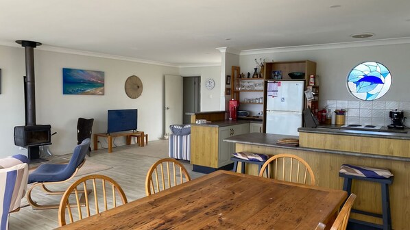 Un salon chaleureux avec une cheminée, un téléviseur et un coin repas comprenant une table et des chaises en bois.