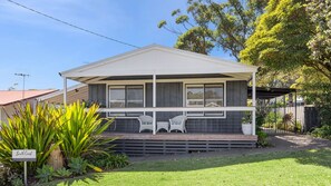 A two-story house with a covered porch, a small garden, and a sign indicating 'South Coast Holidays.' - The Bridge Walk is close to the beach (Manyana)