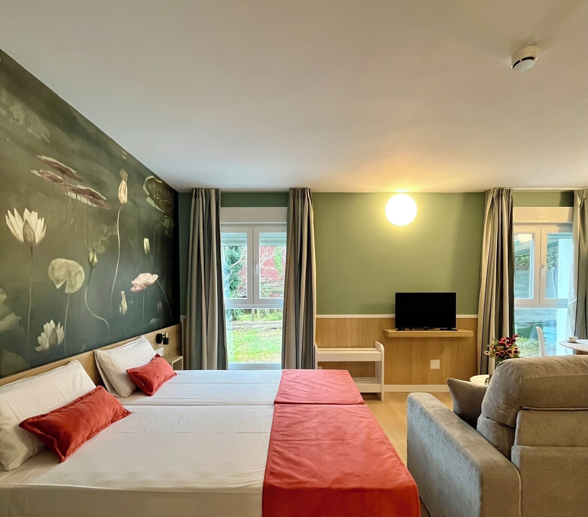 A hotel room with two beds, a TV, a sofa, and a view of the outdoors.