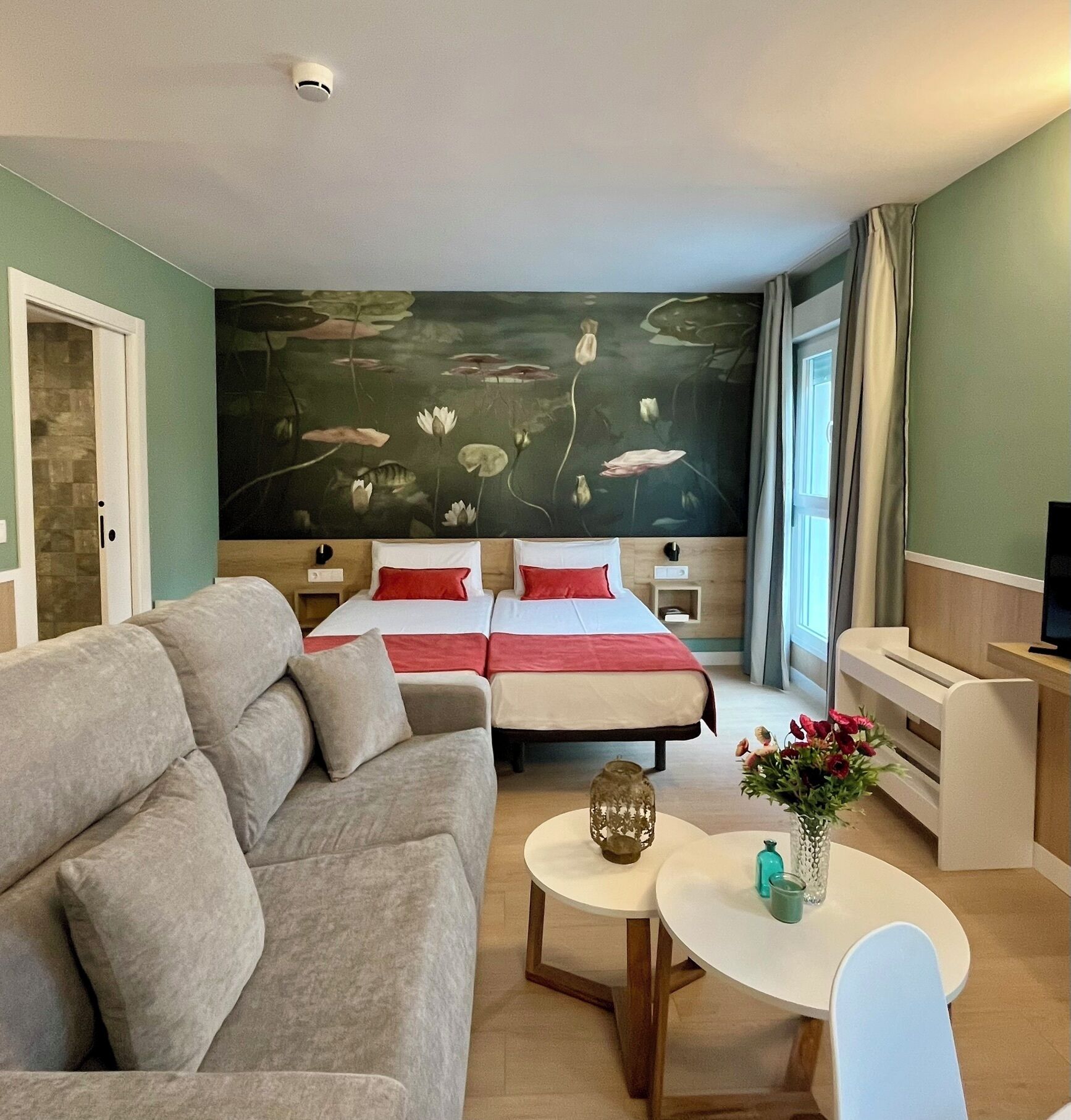 Et hotelværelse med en stor seng, en sofa, et lille bord og et fjernsyn.