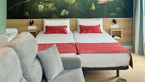 A bedroom with two beds, a sofa, a nightstand, and a wall mural of flowers. - Luxury Singular Apartments Padrón (Padron)