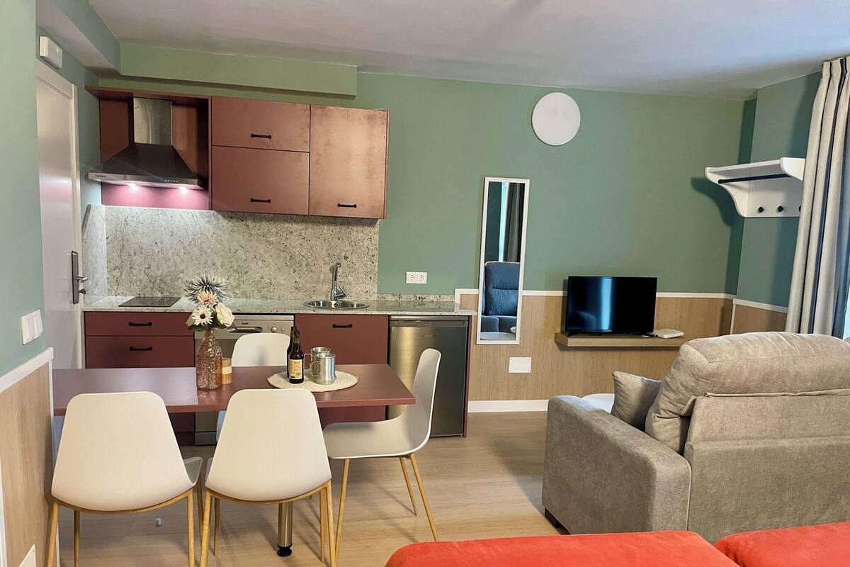Un espace de vie compact comprenant un coin cuisine, un coin repas et un coin salon.