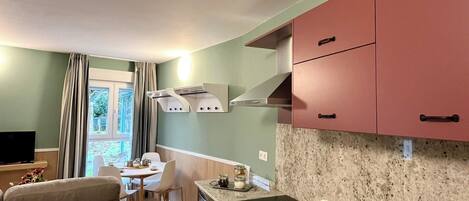 A compact kitchen with a sink, countertop, and cabinets. There is a dining area with a table and chairs.