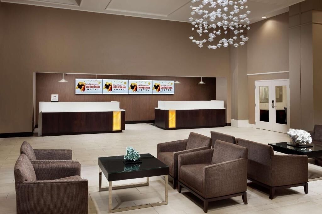 A hotel reception area with two reception desks, a chandelier, and seating arrangements.