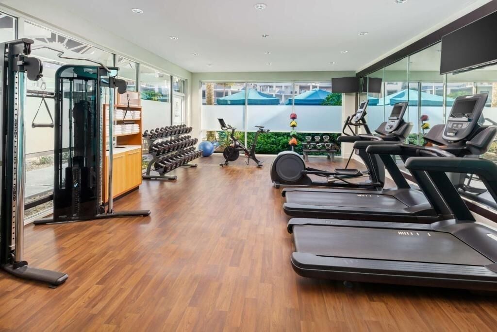 Een moderne sportschool met loopbanden, krachtapparaten en fitnessballen.