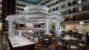 Un restaurant à plusieurs niveaux, doté d’un bar central, de nombreuses tables et d’un décor intérieur moderne.
