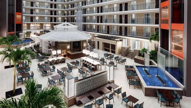 Ein mehrgeschossiges Hotelatrium mit Bar, Essbereich und Pool im Zentrum.