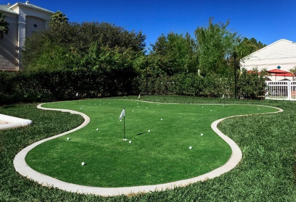 Un campo de mini golf bien cuidado, con un mástil de bandera y varias pelotas de golf.