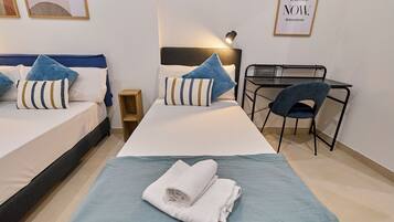 Ein Hotelzimmer mit zwei Betten, einem Schreibtisch, einem Stuhl und einem kleinen Nachttisch.