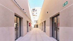 A corridor with glass doors on either side, leading to a building with a clear sky above. - Sant Adrià Urban Suites by gaiarooms (Badalona)