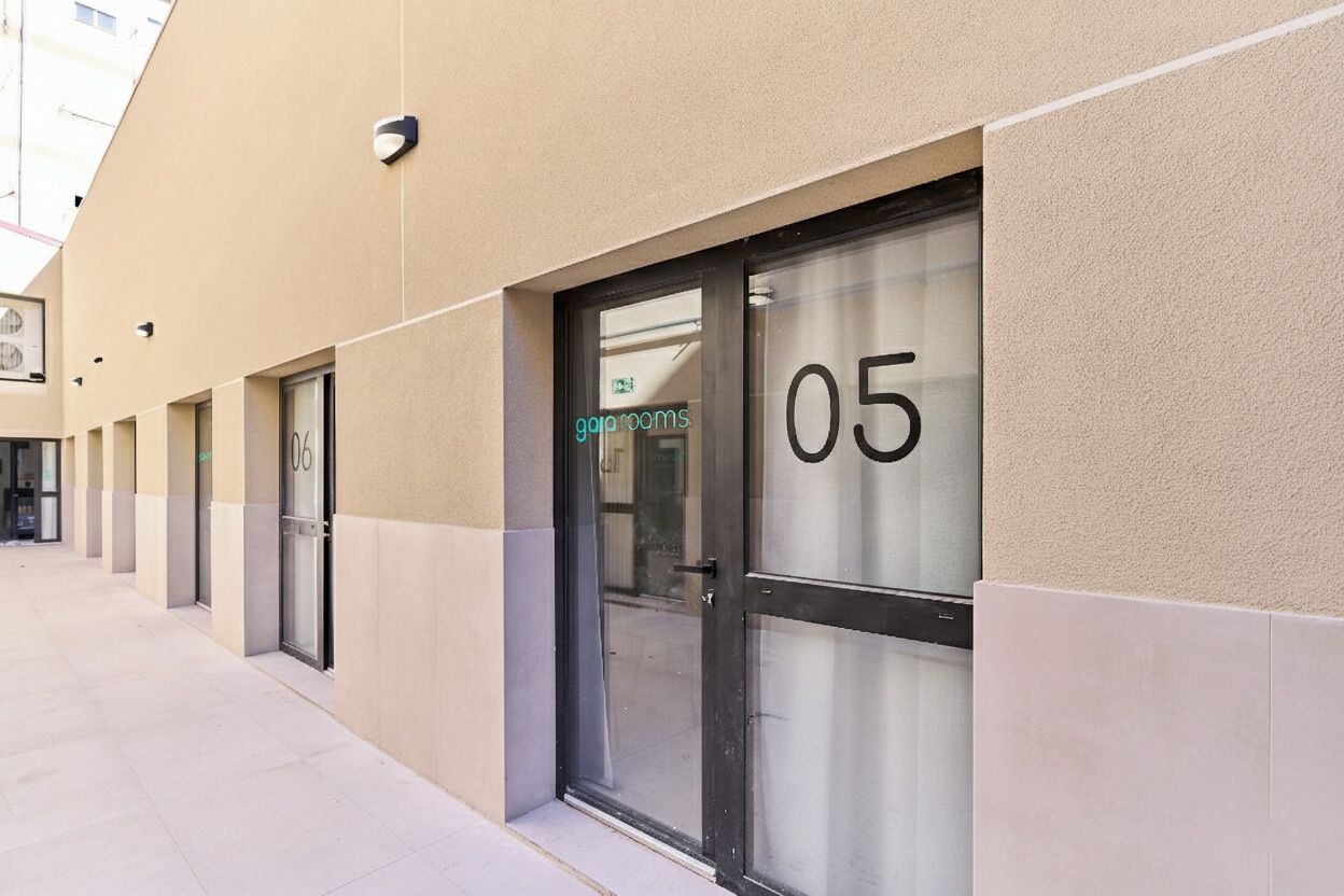 A row of hotel rooms with glass doors, numbered 04 and 05, and a visible sign for 'goprooms'.