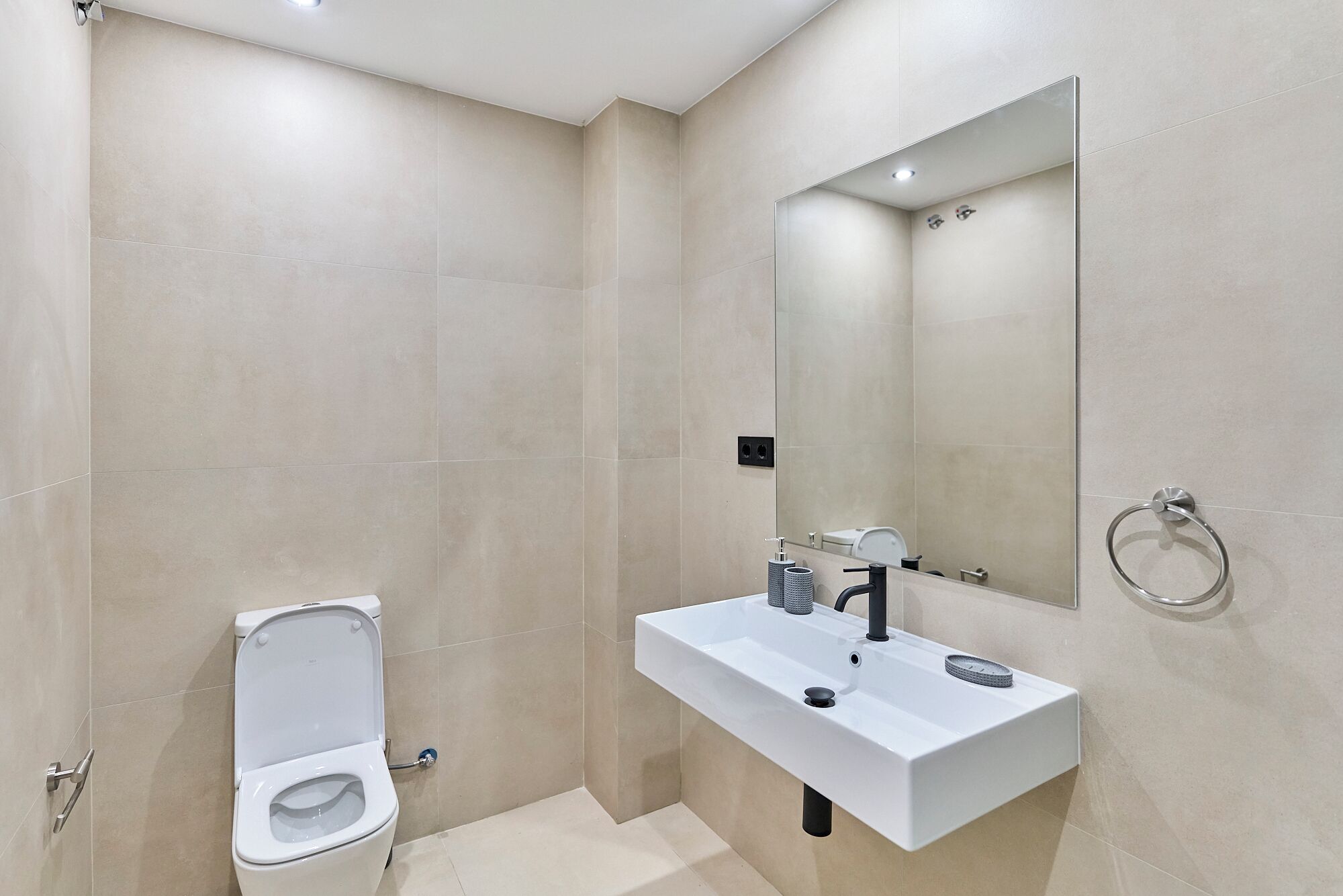 A modern bathroom with a toilet, sink, and mirror.
