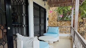 A covered outdoor seating area with two white sofas and blue cushions, a stone wall, and a metal gate. - Borabora Beachfront Malindi Villa  (Malindi)