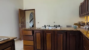 A kitchen with a central island, wooden cabinets, and a tiled floor. - Borabora Beachfront Malindi Villa  (Malindi)