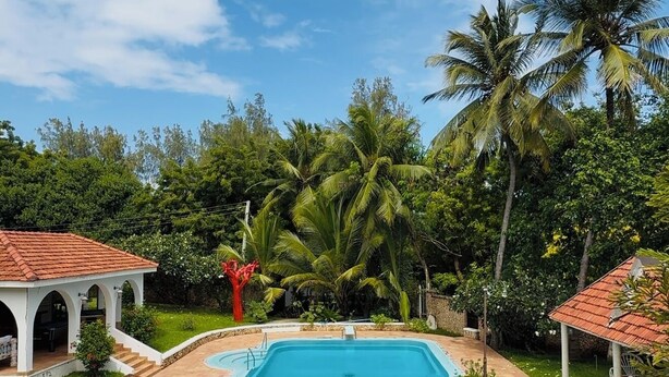 A swimming pool with a curved edge, surrounded by a tiled deck and lounge chairs. - Borabora Beachfront Malindi Villa  (Malindi)