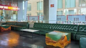Un interior moderno con un sofá de cuero verde, una mesa de centro de vidrio y vistas a un edificio con un cartel de 'NO FUMAR'.