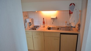 A compact kitchen with a sink, countertop, and wooden cabinets. - Ferienwohnung im Dachgeschoss, Homberg (Homberg)
