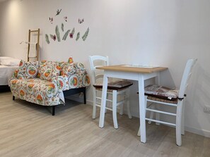 Ein Zimmer mit einem Bett, einem Tisch, zwei Stühlen und einer Wand mit einem Blumenmuster.