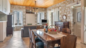 Une cuisine avec un mur en pierre, un plafond en bois et une table à manger avec des chaises.