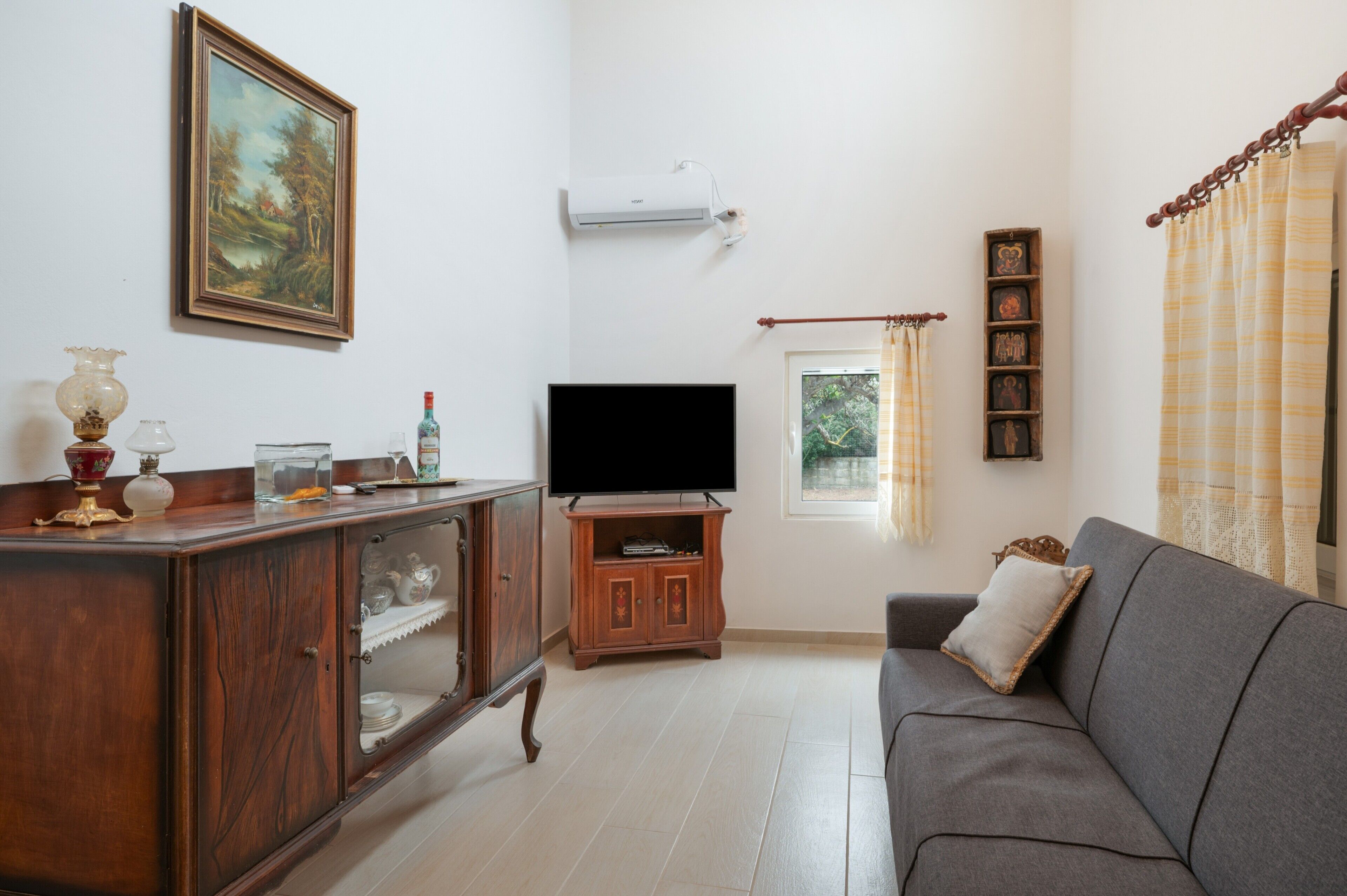Un salon avec un téléviseur, un meuble en bois et un canapé.