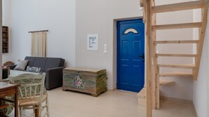 Ett rum med en blå dörr, en träbänk, en soffa, ett litet bord och en dekorativ kista.