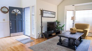 A living room with a TV, sofa, coffee table, and a door.