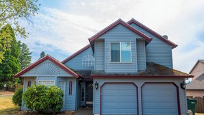A two-story house with a blue exterior and red trim, featuring a garage and a front door.
