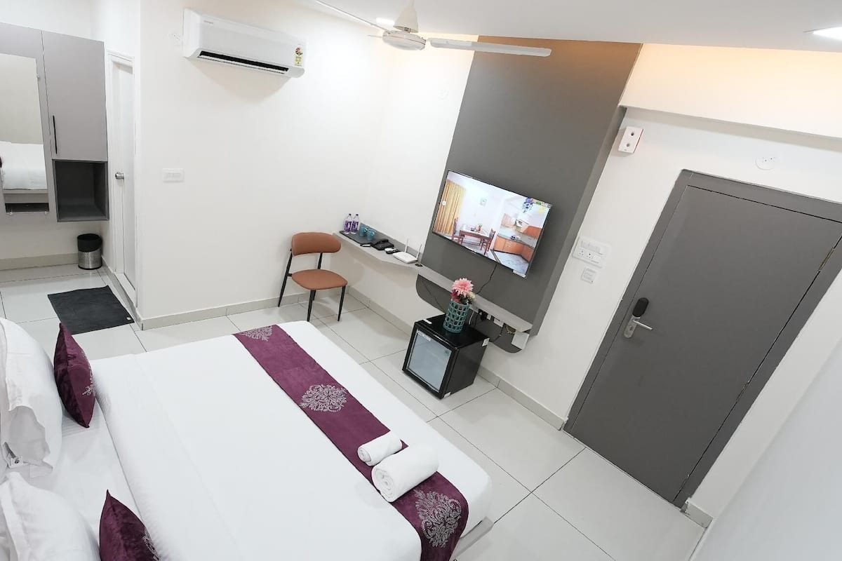 Een hotelkamer met een bed, een bureau, een stoel, een televisie en een kledingkast.
