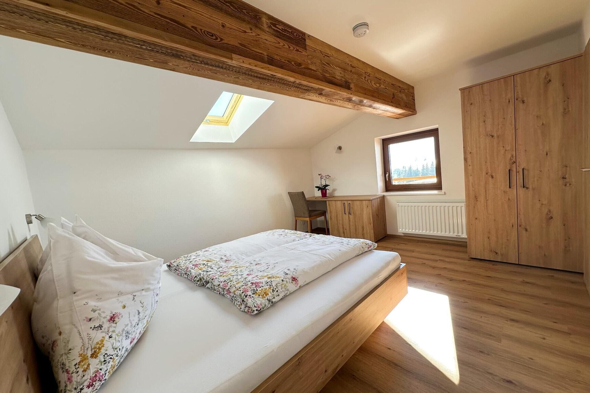 Ein Schlafzimmer mit Galeriebett, Dachfenster, Holzbalken, einem Fenster und einem Kleiderschrank.