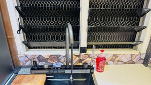Una cucina con lavello, tagliere e una bottiglia rossa di detersivo per piatti.