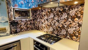 Una cucina con zoccolo posteriore effetto pietra, forno a microonde, piano cottura a gas ed elettrodomestici.
