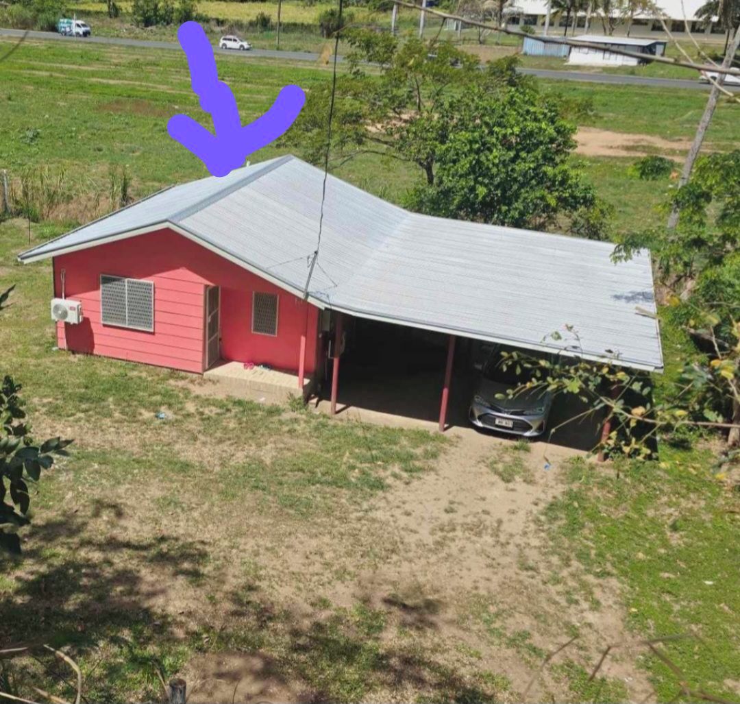 A red single-story house with a metal roof and a garage.