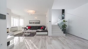 Ein modernes Wohnzimmer mit grauem Sofa, einem Couchtisch und einer Treppe, die zu einer oberen Etage führt.