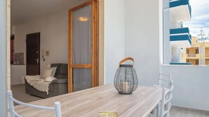 A modern living room with a wooden dining table, a grey sofa, and a decorative lantern. - Cozy Apartment with free private parking (Alghero)