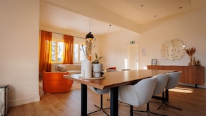 Ein moderner Essbereich mit Holztisch, grau gepolsterten Stühlen und einer Pendelleuchte.