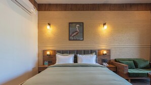 A hotel room with a large bed, two bedside tables with lamps, a green armchair, and a framed picture on the wall. - Trideus The Wild Fraser Corbett (Kaladhungi)