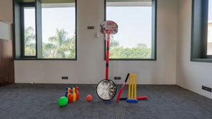 Een kamer met een basketbalring, een dartbord en een bowlingset.