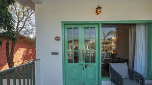 A green door with a number plate, a balcony with a railing, and a view of a building in the background. - Trideus The Wild Fraser Corbett (Kaladhungi)